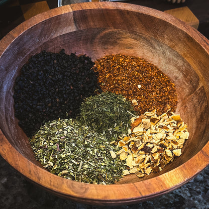 Winter Immune Tea in wooden bowl, a herbal blend infused with ingredients like Rooibos, Echinacea, Nettle Leaf, Elderberry, and Orange Peel, designed to support immune health during the winter season.